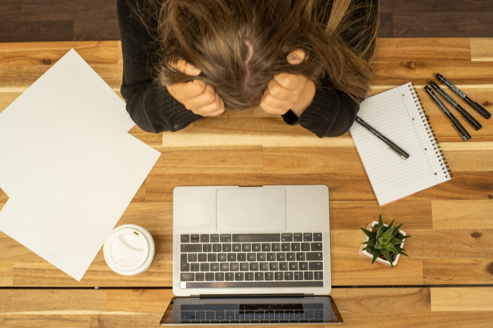 Personne stressée à un bureau avec ordinateur, carnet et documents